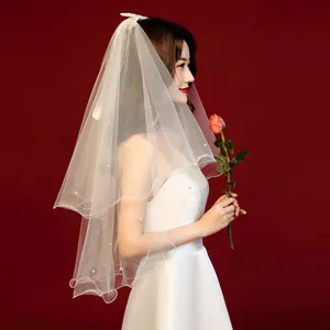 Elegant side view of short white bridal veil featuring pearl accents and a silk bow