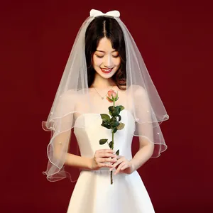 Detailed macro view of elegant white short bridal veil decorated with pearls and bow