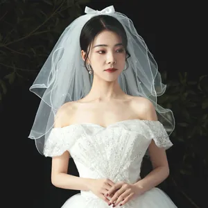 Elegant short white wedding veil with delicate pearl accents and a satin bow for brides