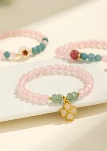 Elegante bracciale di perle in quarzo rosa e agata con ciondolo a quadrifoglio dorato.