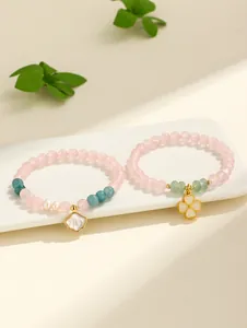 Primo piano di braccialetti in quarzo rosa e agata con ciondoli a conchiglia e quadrifoglio.