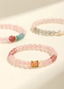 Primo piano di un bracciale in quarzo rosa e cristallo di fragola con perla smaltata.