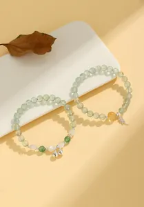 Detailed macro shot of natural light green grape stone beaded bracelets with silver bell charms