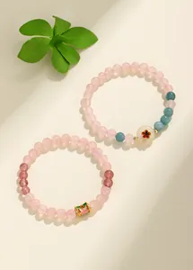 Primo piano di braccialetti con perline di quarzo rosa e fragola con ciondoli