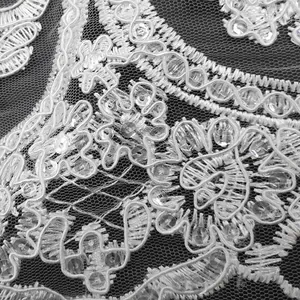 Detail van wit geborduurd pailletten kant met fijn bloemen mesh patroon