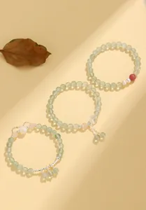 Detailed shot of prehnite and freshwater pearl beaded bracelets with butterfly charms.