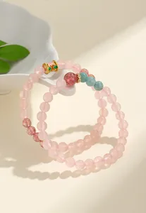 Dettaglio macro di braccialetti con perline in quarzo rosa e quarzo fragola e charm