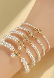 Detailed view of four layered faux pearl bracelets with elegant gold spring clasps.