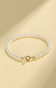 Elegant pearl bead bracelet with gold clasp on a warm beige background