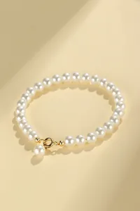Detailed view of an elegant white pearl beaded bracelet with a gold-tone lobster clasp