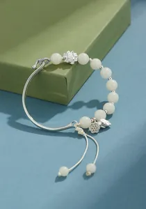 Detalle de pulsera de semillas de bodhi blancas con amuleto de loto y diseño semi-rígido