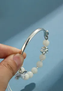 Primer plano de una pulsera de cuentas de Bodhi blancas con dije de mariposa