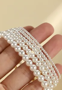 Close-up detail showing the lustrous texture of various sized white pearls on a layered bracelet