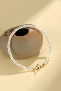 Macro detail of elegant white pearl beaded bracelet featuring a gold spring ring clasp.