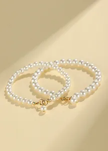 Detailed close-up of elegant white pearl bracelets with gold-tone lobster clasps