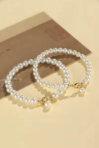 Close-up view of two minimalist white pearl bracelets with gold lobster clasps