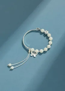 Vista detallada de pulsera de semillas de Bodhi blancas con dije de mariposa