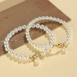 Elegant white faux pearl beaded bracelet featuring gold lobster clasp and a dangling charm