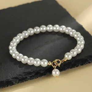 Elegant white beaded pearl bracelet with gold-tone clasp and dangling pearl charm for women