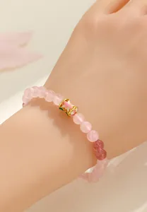 Dettaglio ravvicinato di un braccialetto in quarzo rosa con charm a fiore in smalto.