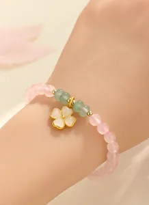 Primo piano di un elegante braccialetto di quarzo rosa e agata verde al polso di una donna