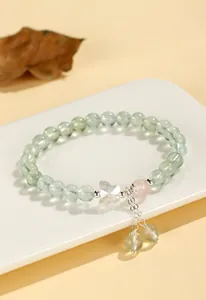 Close-up detail of prehnite gemstone beaded bracelet with a crystal butterfly charm