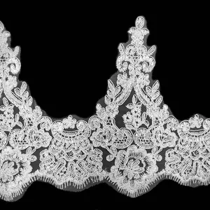 Dettaglio di pizzo ricamato con fiori e paillettes bianche su sfondo nero