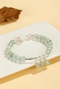Close-up detail of a prehnite and rose quartz beaded bracelet with silver twisted bars and charms