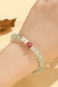 Detail shot of a beaded bracelet with green prehnite, white pearls, and rose quartz bead.