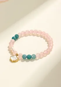 Dettaglio di un bracciale di perline con quarzo rosa, agata blu e ciondolo a conchiglia.