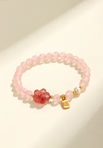 Dettaglio del bracciale in quarzo rosa con fiore di cristallo fragola e ciondolo dorato fortuna