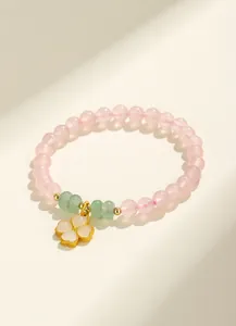 Vista dettagliata di perle in quarzo rosa e ciondolo a quadrifoglio su un bracciale