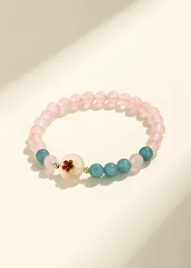 Primo piano di un braccialetto di perle fatto a mano con quarzo rosa e motivo floreale.