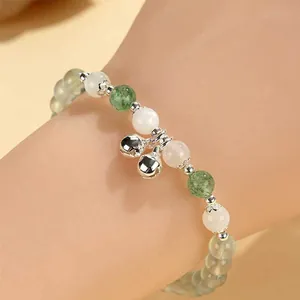 Elegant prehnite and white bead bracelet with double silver bell charms on wrist
