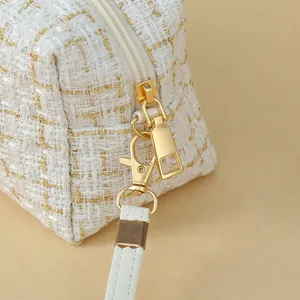 Elegant white tweed cosmetic bag with golden thread and metal zipper details