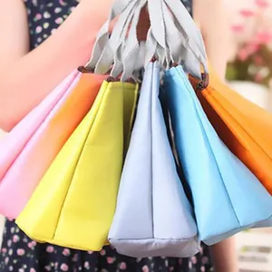 Nahaufnahme verschiedener bunter, leichter, faltbarer Oxford-Stofftaschen in der Hand