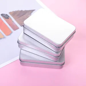 Close-up of frosted silver rectangular tin boxes stacked neatly on a pink surface