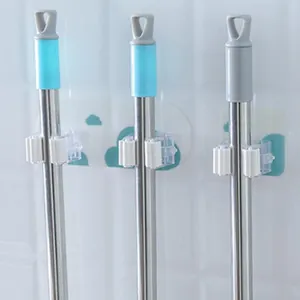 Nahaufnahme von wandmontierten Mop- und Besenhalter-Clips an einer weißen Fliesenwand