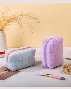 Twee zachte gewatteerde make-uptassen van pluche in lavendel en blauw met borstels