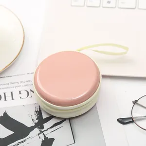 Dettaglio di una custodia rotonda rosa macaron con cerniera per monete e cuffie, stile mini