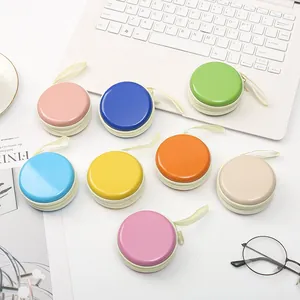 Collezione di mini portamonete rotondi in latta color macaron su scrivania bianca