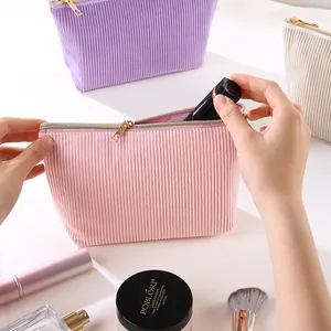 Nahaufnahme einer rosa Cord-Kosmetiktasche mit goldenem Reißverschluss, gefüllt mit Make-up