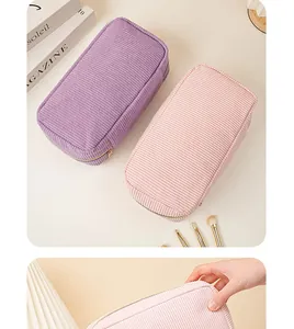 Close-up of pink corduroy makeup bag being held showing the soft ribbed fabric texture
