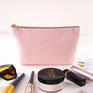 Nahaufnahme der rosa Cord-Kosmetiktasche mit Make-up-Zubehör auf einem Tisch