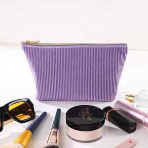 Detailansicht einer lila Cord-Kosmetiktasche umgeben von verschiedenen Make-up-Artikeln