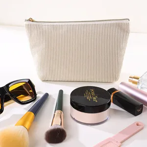 Nahaufnahme einer weißen Cord-Kosmetiktasche umgeben von professionellem Make-up-Zubehör