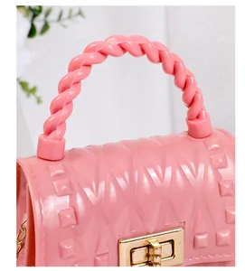Detail der rosa Gelee-Tasche mit goldenem Drehverschluss und gewebtem Griff.