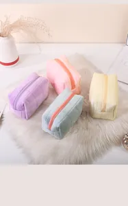 Vier pastelkleurige pluche gewatteerde make-up tassen op een zacht wit nepbontkleedje