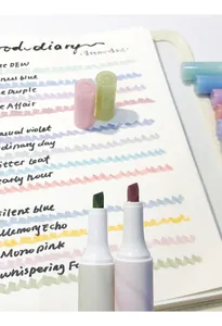 Nahaufnahme von Textmarker-Spitzen mit verschiedenen Pastellfarben in einem Notizbuch.