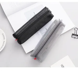 Detail view of black and grey transparent mesh pencil cases on an open book background